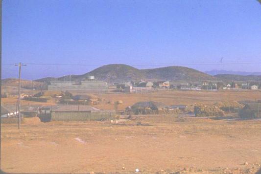 A view of the group compound from the village showing the hill in the background that the C-124 had to clear when taking off from K-14