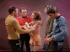 Kirk grabs female alien as McCoy, Scotty look on